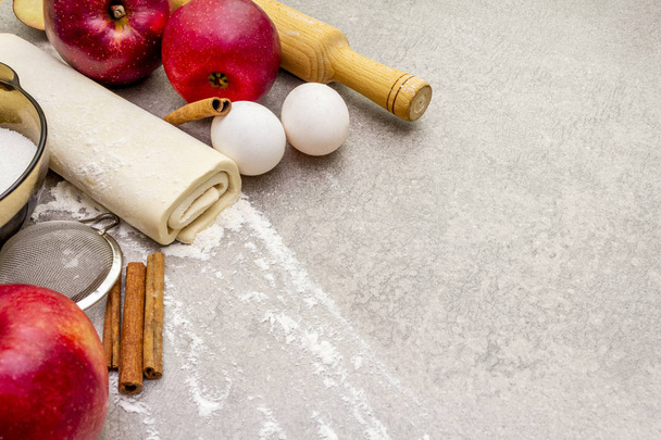 Apple pie ingredients baking concept. Fresh apples with cinnamon, flour, sugar, eggs. Cooking process on stone background, copy space - Photo, Image