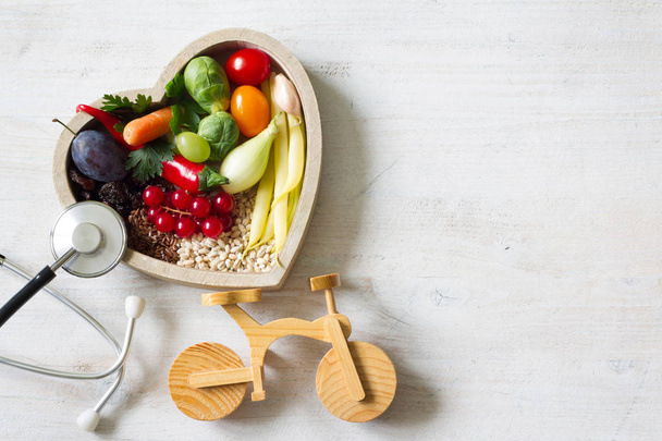 Healthy food in heart with stethoscope and bike diet sport lifestyle concept - 写真・画像