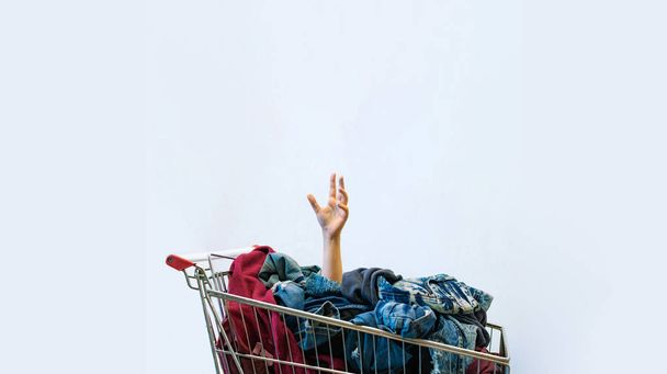 Shopaholic concept. Female hand sticks out of shopping cart - Photo, Image