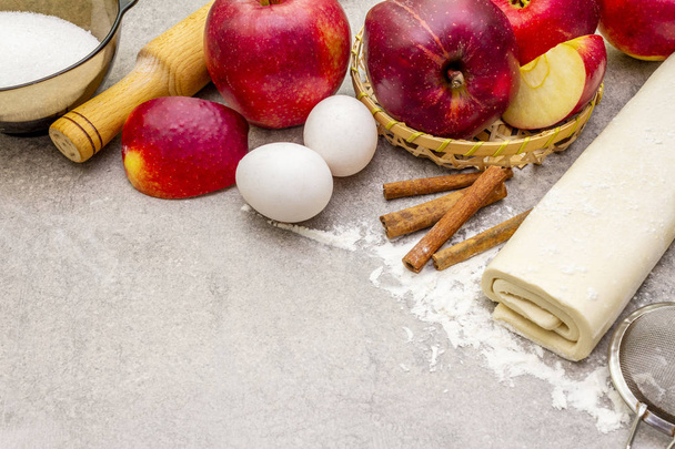 Apple pie ingredients baking concept. Fresh apples with cinnamon, flour, sugar, eggs. Cooking process on stone background, close up - Photo, Image