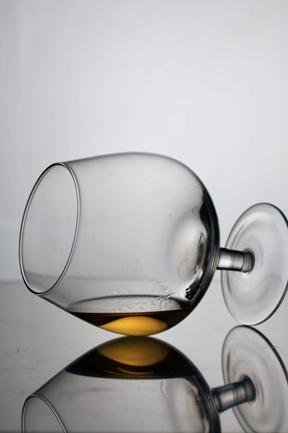 Short-stemmed wine glass. Lies on its side, photographed in the light. It has a small amount of alcohol. - Φωτογραφία, εικόνα