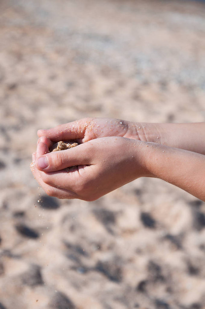 Песок вытекает из рук. На пляже у моря
 - Фото, изображение