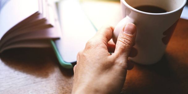 Hands with a phone and cup of coffee - 写真・画像