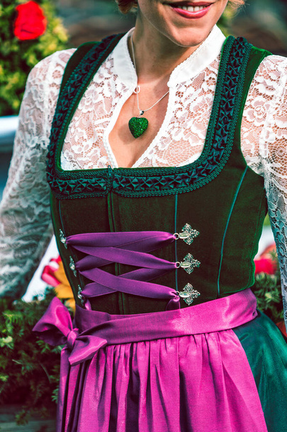 Szczegóły zielony projektant dirndl wykonane z aksamitu z fioletowym fartuchem i białą koronkową bluzką - Zdjęcie, obraz