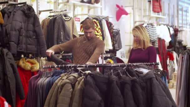 Young woman helps her man to choose a jacket - Footage, Video