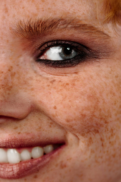 Closeup macro portrait of female face. Human woman half-face with day beauty makeup. Girl with perfect skin and freckles. - Photo, image