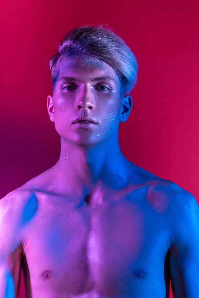 Handsome pumped up guy with naked torsos. Sports guy, attractive male body. Studio shooting with color filters - Fotografie, Obrázek