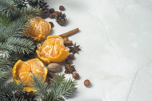 Tangerines without peel, Christmas tree branches, spices, cinnamon, cones on a white stone background. Concept of Christmas, New Year, Mulled Wine - Foto, Imagen