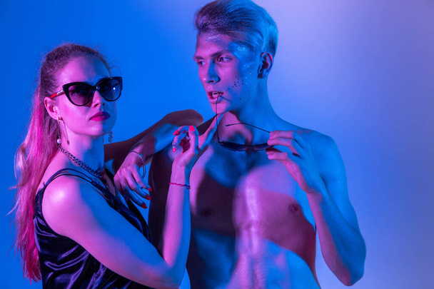 Modelki męskie i żeńskie w studiu z filtrami kolorów. Zbliżenie modeli w neonowym fioletowym i niebieskim świetle - Zdjęcie, obraz