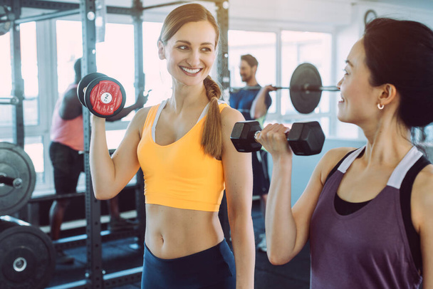 Дві жінки займаються фітнес-тренінгом разом у спортзалі
 - Фото, зображення