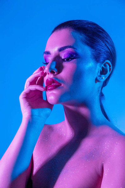 Gorgeous brunette model in the studio with color filters. Fashion, beauty, glow. Closeup face of a beautiful brunete woman in neon light purple and blue. - Φωτογραφία, εικόνα