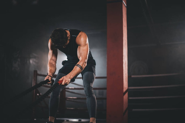 Poseren bodybuilding man toont zijn spier in een zwarte Studio in de voorkant van de camera dragen professionele sportkleding - Foto, afbeelding