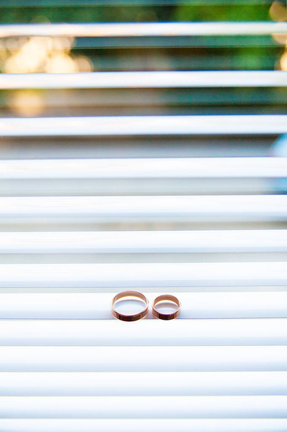 Két gyönyörű jegygyűrű az ablakredőnyön. - Fotó, kép