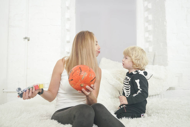 mother and child painting pumpkin together on white room background sitting on the sofa - Photo, Image