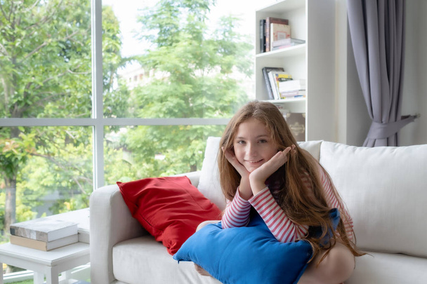 маленькая девочка улыбается и сидеть с подбородком отдыхает на руке у себя дома, y
 - Фото, изображение