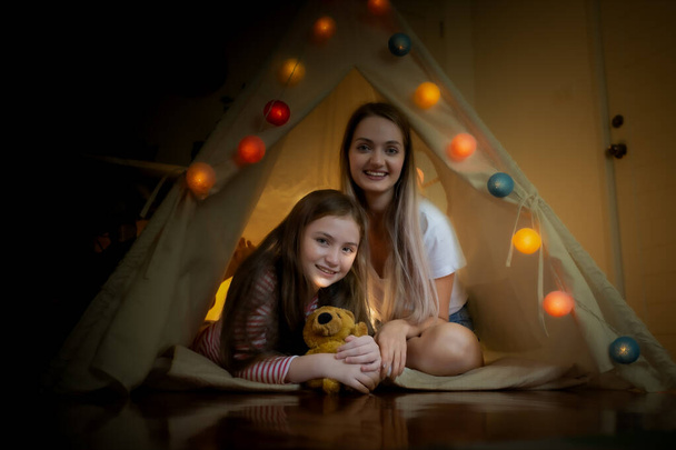 boldog kislány és anya mosolyog, és játszani kemping sátrakban a - Fotó, kép