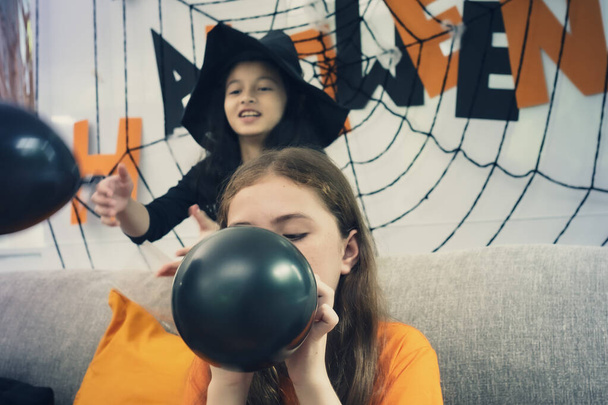 Маленькие девочки готовят игрушечный шарик для украшения на Хэллоуин
 - Фото, изображение