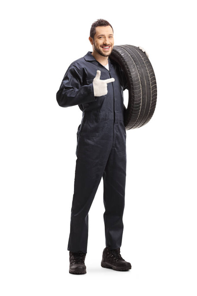 Mechanic holding a of car tire and pointing - Фото, изображение