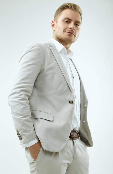 Handsome blonde man model in a fashion gray suit in studio - Фото, изображение