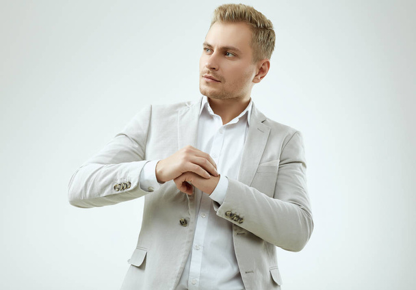 Handsome blonde man model in a fashion gray suit in studio - Photo, Image