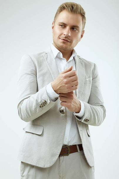 Handsome blonde man model in a fashion gray suit in studio - Photo, Image
