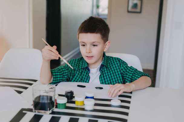 Beautiful little boy having fun painting with water colors at home - Foto, Imagen