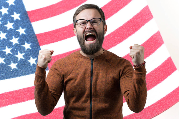 Portrait of a young guy spectacled on the background of the USA flag. Concept of patriotism - Photo, Image
