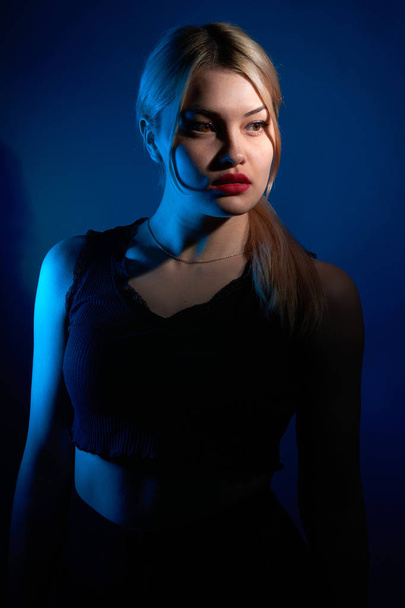 portret van een mooi meisje met rode lippen op een blauwe achtergrond - Foto, afbeelding