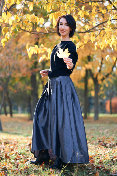 Beautiful elegant woman standing and posing in a city park in autumn - Photo, Image