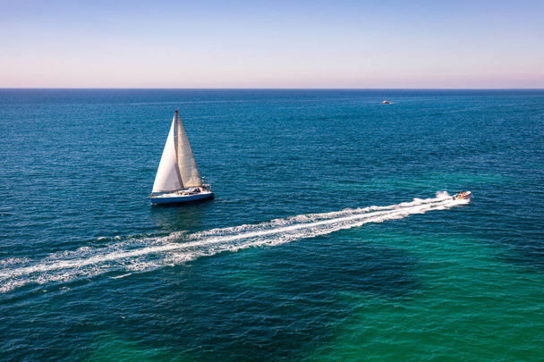 Witte zeilboot geïsoleerd in blauw zeewater. Zeilboot in de zee  - Foto, afbeelding