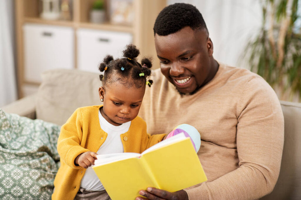 african father reading book for baby daughter - Foto, Imagen