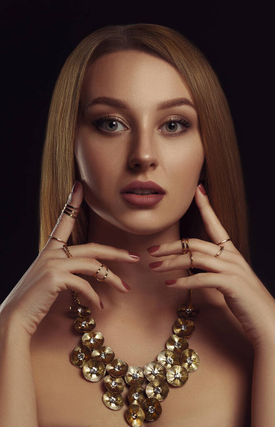 Portrait of pretty adult girl wearing golden necklace on black background - Fotografie, Obrázek