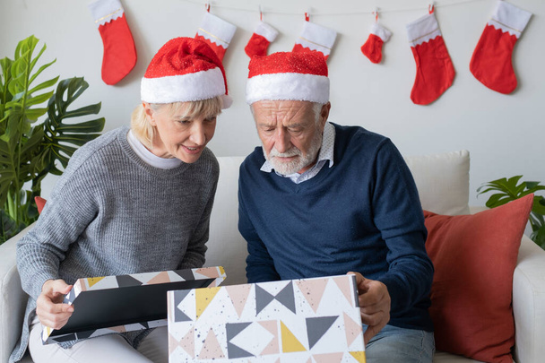 senior elderly caucasian old man and woman help open big gift pr - 写真・画像