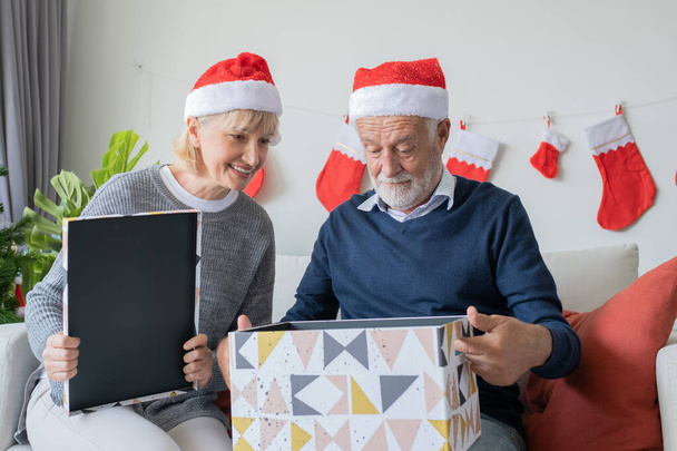 пожилые кавказский старик и женщина помочь открыть большой подарок Pr
 - Фото, изображение