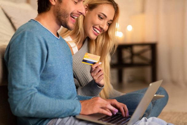 Пара за допомогою ноутбука і кредитної картки робить замовлення вдома
 - Фото, зображення