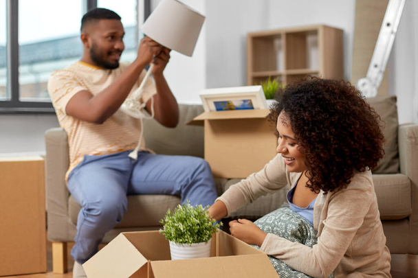 happy couple packing boxes and moving to new home - Φωτογραφία, εικόνα