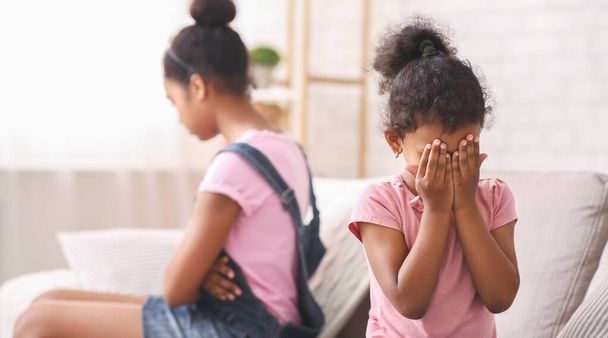 kleines afrikanisches Mädchen weint zu Hause und wird von ihrer älteren Schwester ignoriert - Foto, Bild