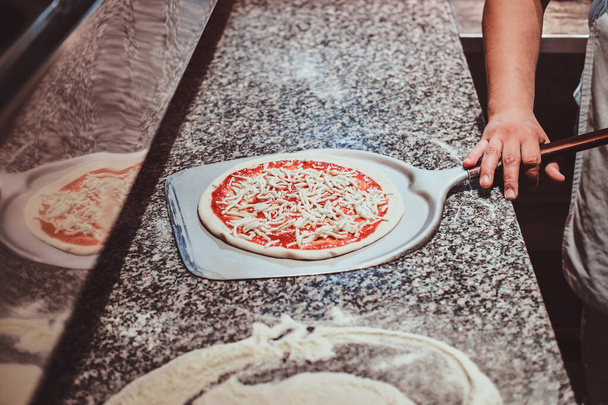 Chef-kok maakt pizza in de keuken van het restaurant - Foto, afbeelding