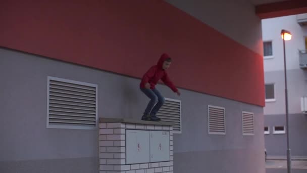 Een kind springt van een bovenbouw van een flatgebouw. - Video