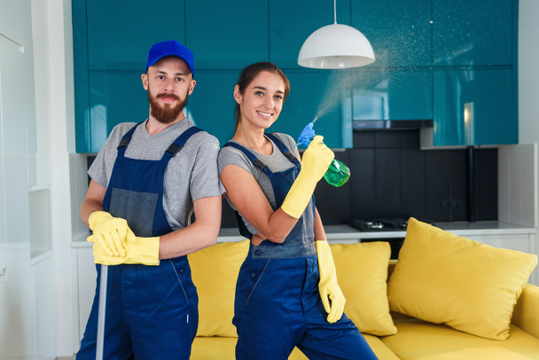 Kilku profesjonalnych sprzątaczy przebywa razem we współczesnej kuchni z detergentami. Koncepcja usług sprzątania domów. - Zdjęcie, obraz