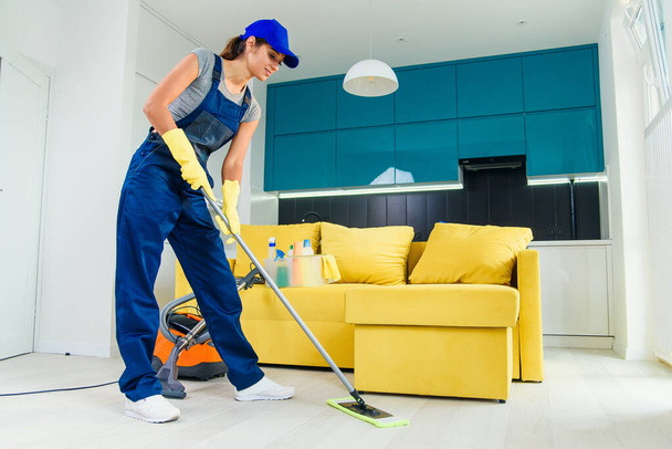 Концепція очищення. Молода жінка миє підлогу на кухні
 - Фото, зображення