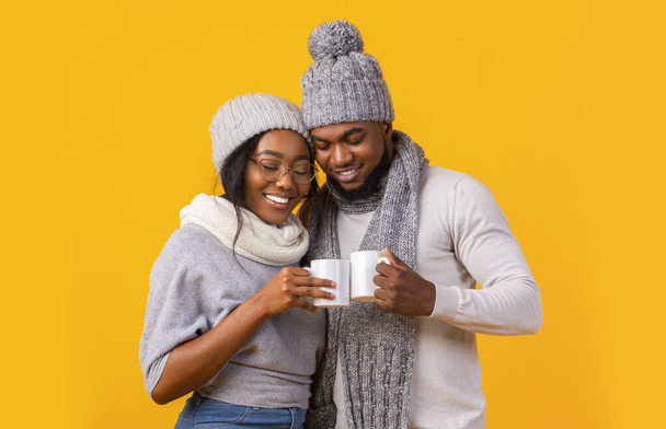 Winter vriend en vriendin drinken koffie over gele achtergrond - Foto, afbeelding