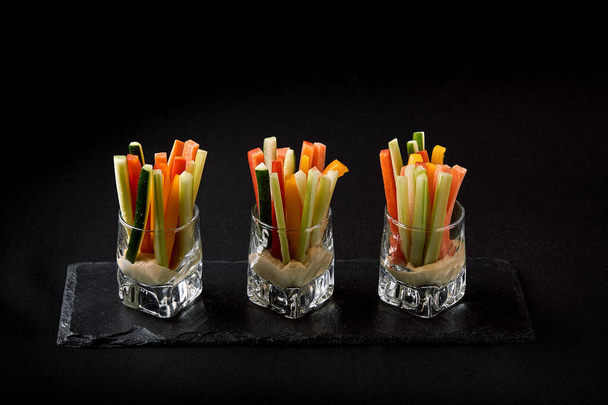 Смачні соковиті огірки, морква, селера, нарізані тонкими смужками або клубами, подаються в склянці як закуски, щоб зануритися в гострий соус. Концепція злиття їжі, низький ключ, простір для копіювання
. - Фото, зображення