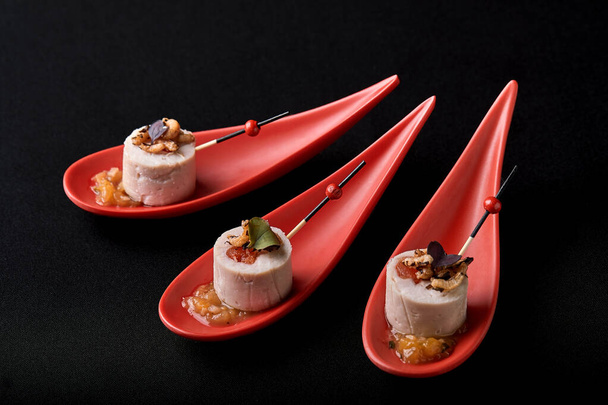 Gänseleberpastete, Foie gras, serviert auf schwarzem Stein in japanischen roten Löffeln. Paste mit Marmelade und Nüssen serviert. Fusion Food Konzept, zurückhaltend, Kopierraum. - Foto, Bild