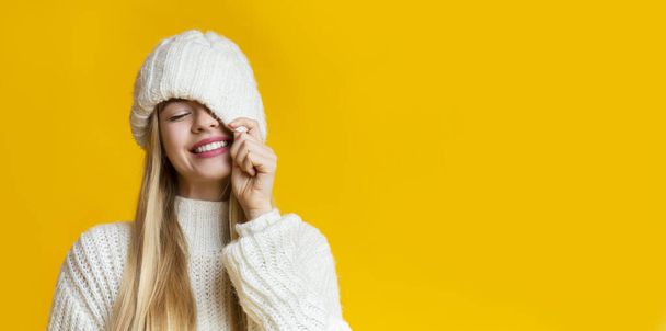 Carefree girl covering her eye with white knitted hat - Photo, image