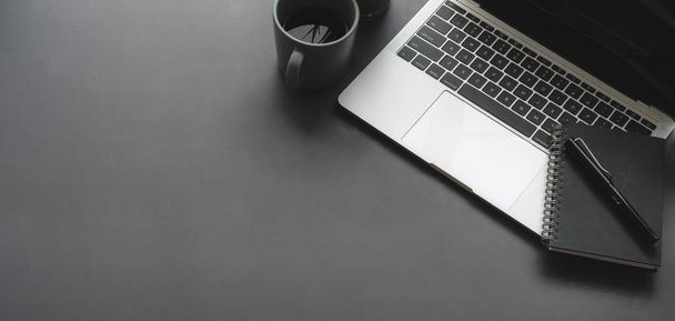 Overhead-Aufnahme von dunklem stilvollem Arbeitsplatz mit Laptop-Computer schwarzes Notizbuch auf schwarzem Tischhintergrund - Foto, Bild