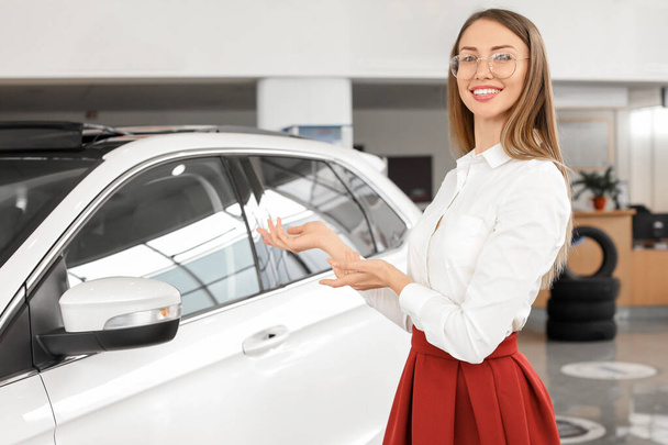 Happy woman near new car in salon - Фото, изображение