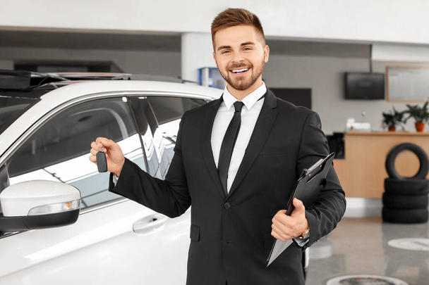 Salesman with car key in modern salon - Φωτογραφία, εικόνα