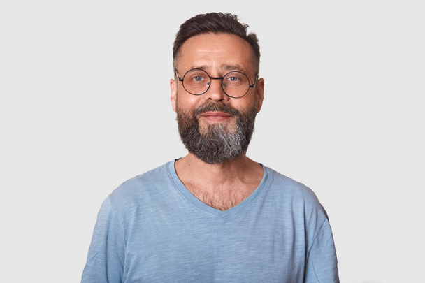Close up portrait of handsome middle aged bearded Caucasian man with smile, male wearing gray casual t shirt, posing isolated over white background, looking directly at camera, looks satisfied. - Фото, зображення
