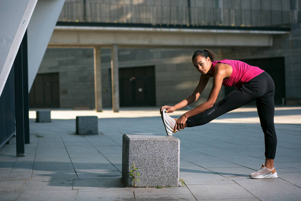 Active professional athlete training outdoors and putting one foot on the stone cube while exercising - Fotó, kép